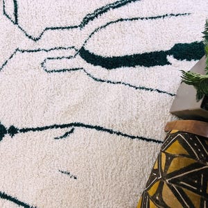 Corner detail of cream Beni Ourain rug showing black geometric patterns and authentic handwoven edge finishing
