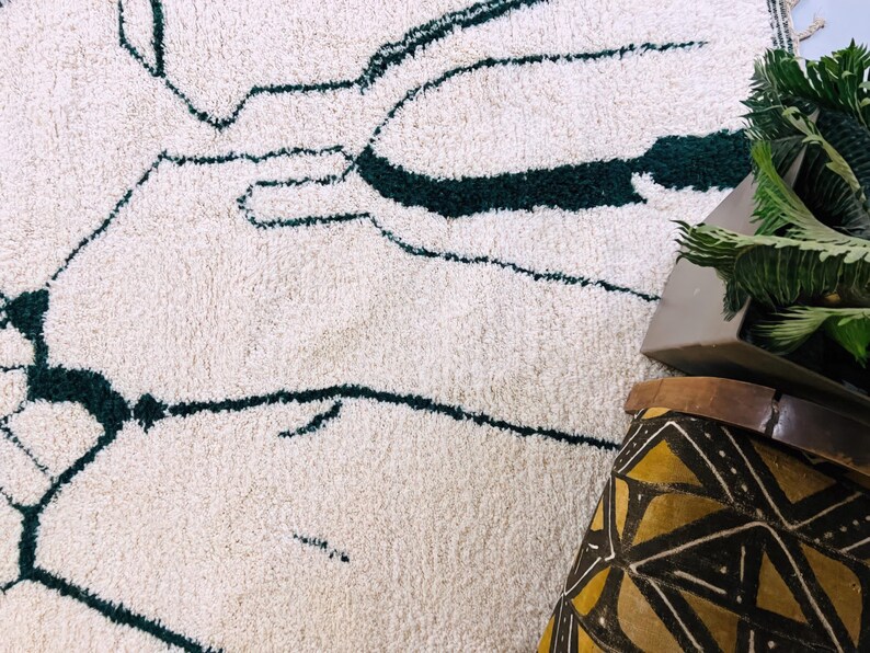 Corner detail of cream Beni Ourain rug showing black geometric patterns and authentic handwoven edge finishing