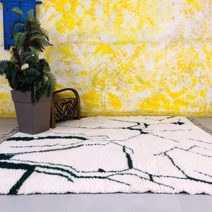 Overhead view of white Beni Ourain rug with black abstract line design on bright yellow backdrop