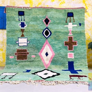 Handwoven green Moroccan rug with abstract geometric symbols.