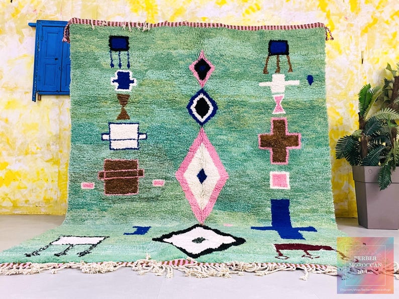 Handwoven green Moroccan rug with abstract geometric symbols.