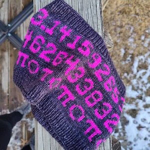 May include: A dark gray knitted headband with a pink alphabet pattern. The headband is made of a soft, comfortable material and is perfect for keeping your ears warm in the winter.