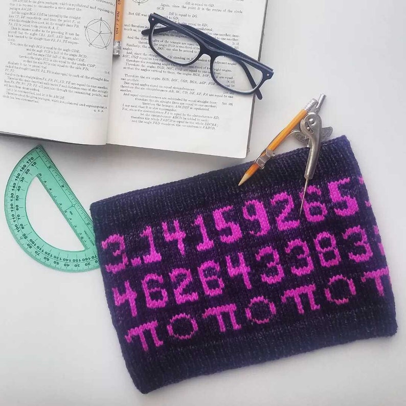 May include: A black knitted pouch with pink embroidered numbers and the symbol pi. The numbers are 3.14159265, 462643383, and pi repeated four times.