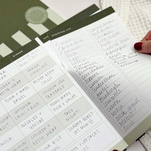 close up of perforated shopping list section being torn off of weekly meal planner page inside A4 notepad