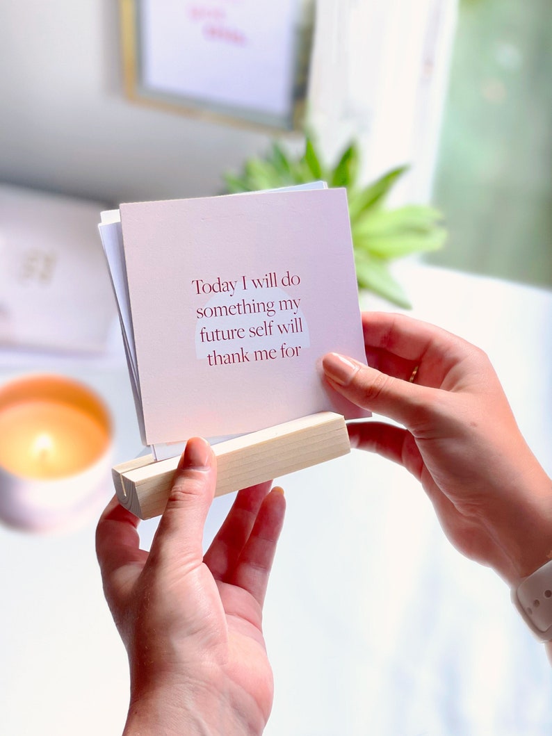 positive daily affirmations pack held in wooden holder on woman's desk