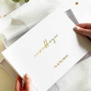 woman holding an A5 landscape died memory book with personalised names and "our wedding day" in an elegant script font written in gold foil