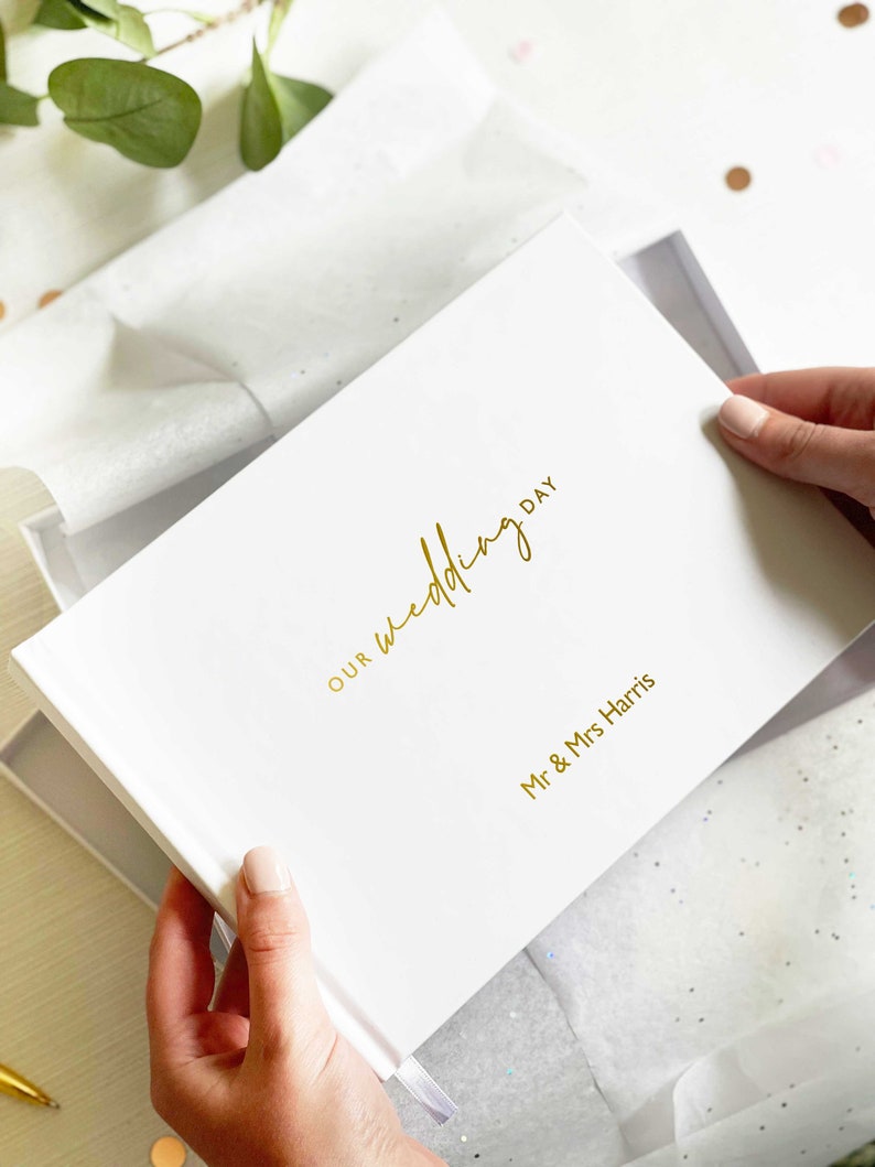 woman holding an A5 landscape died memory book with personalised names and "our wedding day" in an elegant script font written in gold foil