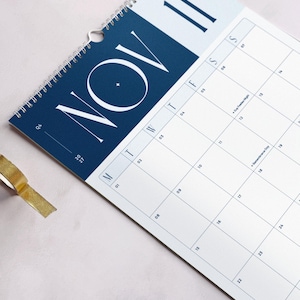 Close up of a monthly calendar showing November 2027 on a light background. The header has large Monday-start planner grid and a bold blue header with modern typography.