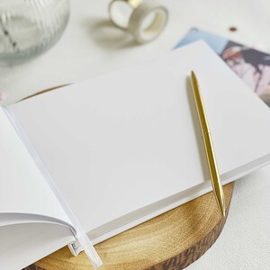 plain inside pages of scrapbook with gold pen resting on sheets