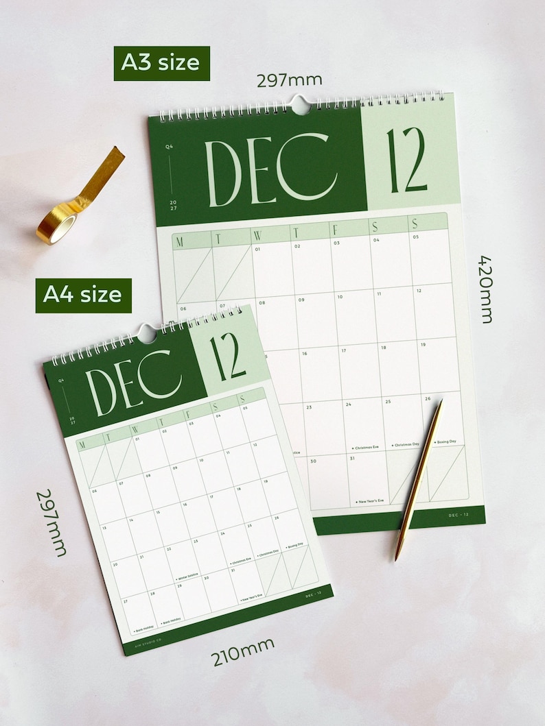 2027 month view calendar showing December with sage green and deep forest green heading and large typographic design. The calendars are on a light surface with large A3 and small A4 size dimensions to show scale between the two options.