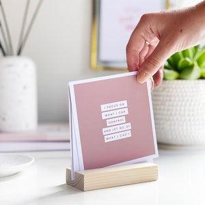 a woman choosing a positive affirmation card to display on her office desk