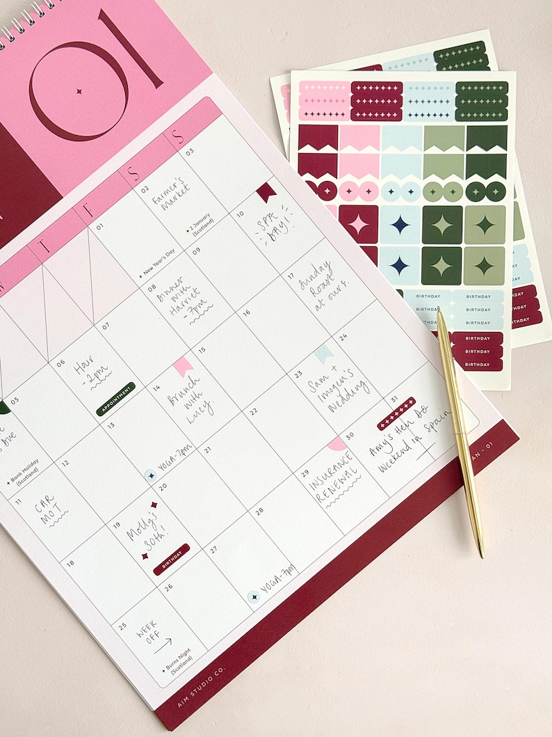 january calendar page on a desk with handwritten plans filled out across the monthly calendar page. A gold pen lies across the corner of the planner, and there are matching sticker sheets next to the calendar and used within the aesthetic layout.