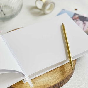 plain inside pages of memory book with gold pen and aesthetic white table setting.
