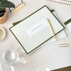 A4 notepad with cover reading productivity planner and deep green outline on beige cover