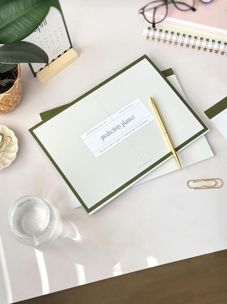 A4 notepad with cover reading productivity planner and deep green outline on beige cover