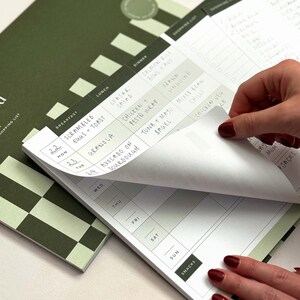 woman removing tear off notepad page from a menu plan notepad