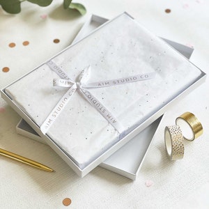 gift boxed personalised memory book presented in elegant tissue wrapping, ribbon and a luxury white gift box with a gold pen next to it