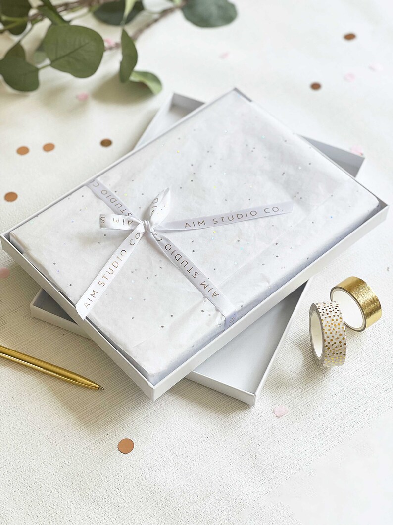 gift boxed personalised memory book presented in elegant tissue wrapping, ribbon and a luxury white gift box with a gold pen next to it