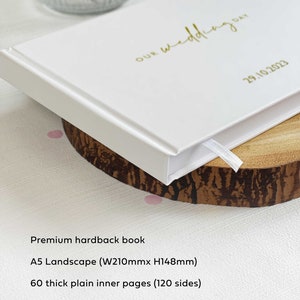 white hardcover A5 memory book with product features listed such as 60 plain inner pages and option to add personalised couples names on the book cover.