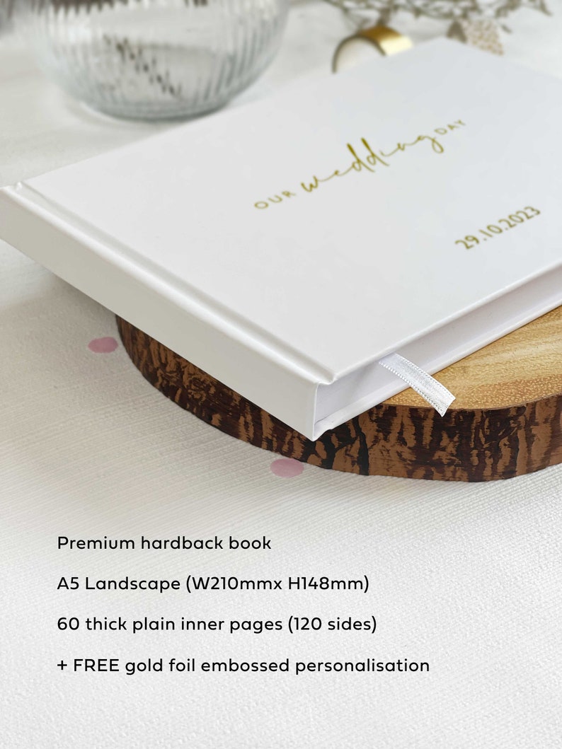 white hardcover A5 memory book with product features listed such as 60 plain inner pages and option to add personalised couples names on the book cover.