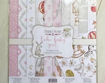 May include: A pack of 10 double-sided scrapbook paper sheets featuring a boho baby girl theme. The paper is 12 inches by 12 inches and has a variety of patterns, including floral, geometric, and animal prints. The pack is labeled "Boho Baby Girl" and "Fabrika Decoru".