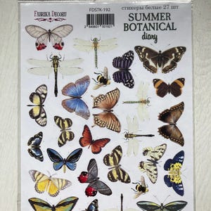 Puede incluir: Un paquete de pegatinas blancas con ilustraciones de mariposas, libélulas y abejas en tonos amarillos, azules, rojos y marrones. El texto "SUMMER BOTANICAL diary" está impreso en el paquete. Las pegatinas son de "FABRIKA DECORU".