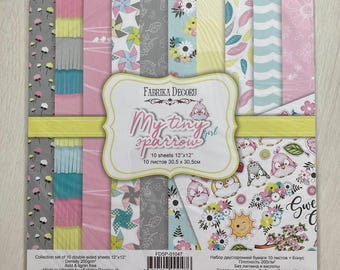 Op de afbeelding: Een set dubbelzijdig scrapbookpapier van Fabrika Decoru, 30,5 cm x 30,5 cm, met patronen in roze, geel, grijs en blauw. Het pakket bevat vellen met bloemen-, vogel- en geometrische ontwerpen. De titel "My Tiny Sparrow" staat op de voorkant.