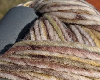 May include: A skein of yarn in a multi-coloured pattern of brown, beige, yellow, and blue. The yarn is wound into a ball shape.