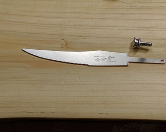 May include: A silver knife with a serrated edge and a handle with the text "Sheffield Stainless Steel England". The knife is separated from its handle, which is a small, round, silver knob.