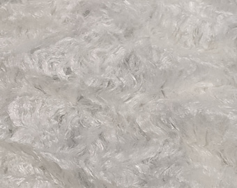 May include: Close-up of a white, fluffy fabric with a textured, wavy surface. The material appears soft and plush, with a dense arrangement of fibres. The overall effect is a cloud-like appearance.