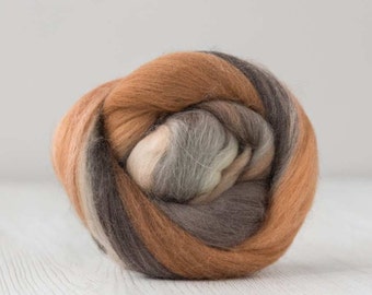 May include: A ball of blended wool roving in shades of brown, tan, and gray. The fibers are tightly wound, creating a textured, layered appearance. Ideal for fiber art, spinning, or felting projects.