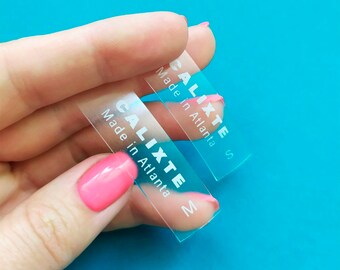 May include: Two clear plastic labels with the text "Calixte Made in Atlanta" and the sizes "S" and "M" printed on them.
