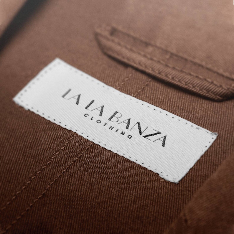 May include: A white label with black text that reads "LALA BANZA CLOTHING" sewn onto a brown fabric.