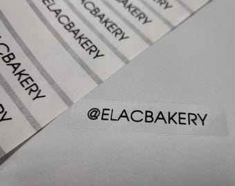 Könnte beinhalten: Ein transparenter Aufkleber mit dem Text "@ELACBAKERY" in schwarzer Schrift.