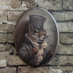 May include: A framed portrait of a squirrel wearing a black top hat and a white ruffled shirt with a bow tie. The squirrel is looking to the right and has a serious expression on its face.