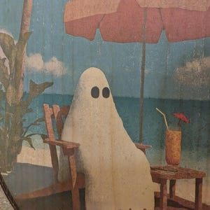 May include: A whimsical illustration depicts a ghost relaxing on a beach chair under a coral-colored umbrella. The ghost, with black oval eyes, enjoys a drink with a tiny umbrella. The background shows a beach scene with palm trees and blue skies.