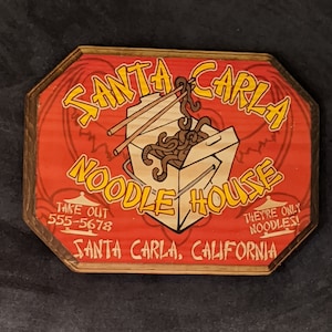 Placa de madeira com o nome do restaurante Santa Carla Noodle House - Os Garotos Perdidos - Impressão artesanal com tinta.