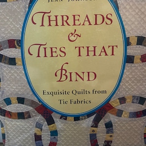 May include: Book cover with a white background and a colorful quilt pattern. The title is "Threads & Ties That Bind: Exquisite Quilts from Tie Fabrics" by Jean Johnson.