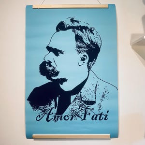 May include: A blue poster with a black and white silhouette of a man with a mustache. The text "Amor Fati" is printed in black at the bottom of the poster.