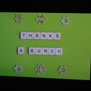 Könnte beinhalten: Eine grüne Karte mit weißen Blumen und den Worten "THANKS A BUNCH", die mit Spielsteinen gelegt wurden.