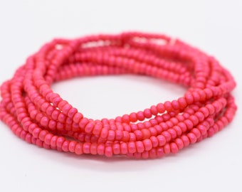 May include: A pink beaded bracelet made of small, round beads. The bracelet is coiled up in a circle.