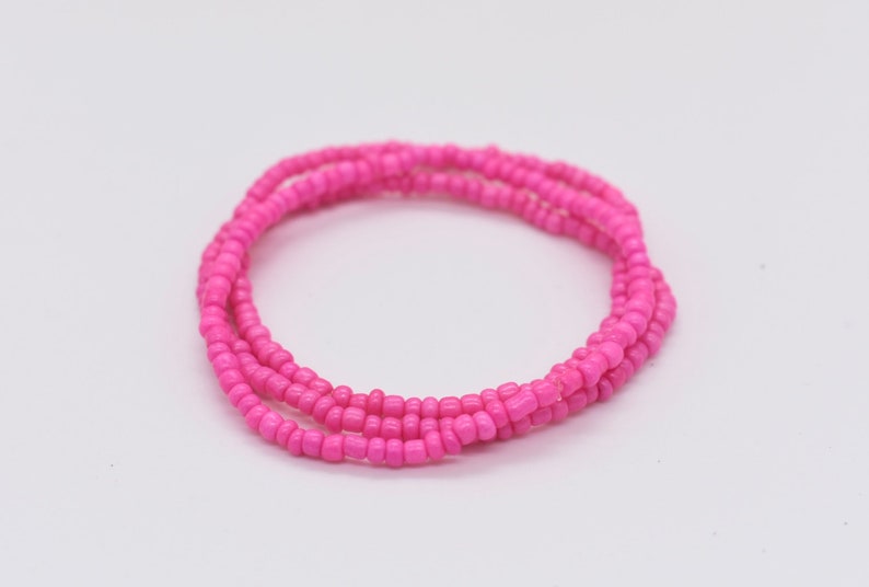 Puede incluir: Un brazalete de cuentas rosa hecho de peque&ntilde;as cuentas redondas. El brazalete est&aacute; envuelto alrededor de s&iacute; mismo varias veces, creando un aspecto grueso y en capas.