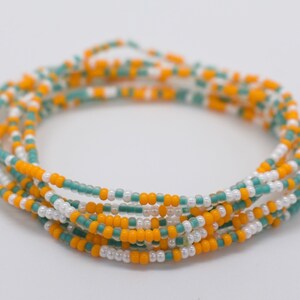 May include: A multi-strand beaded bracelet with white, yellow, and teal beads.