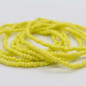 May include: A yellow beaded waist bead necklace, also known as a waist chain, is made of small, round beads strung together. The beads are a bright, vibrant yellow color and are arranged in a simple, elegant design.