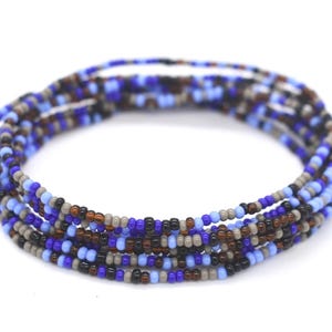 May include: A multi-strand beaded bracelet with blue, brown, and gray beads. The bracelet is made of small, round beads that are strung together in a random pattern.