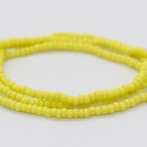 May include: A yellow beaded bracelet with multiple strands of beads.