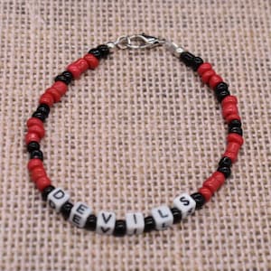 May include: A red and black beaded bracelet with the word "DEVILS" spelled out in white beads.