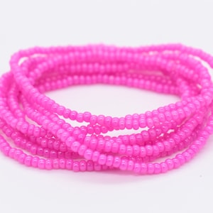 Può includere: Un braccialetto di perline rosa fatto di piccole perline rotonde. Il braccialetto è avvolto su se stesso più volte, creando un aspetto spesso e stratificato.