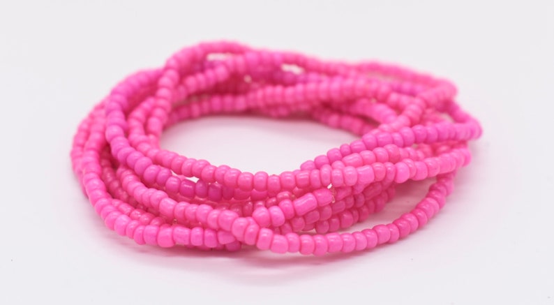 Puede incluir: Un brazalete de cuentas rosadas hecho de peque&ntilde;as cuentas redondas. El brazalete est&aacute; envuelto alrededor de s&iacute; mismo varias veces, creando un aspecto grueso y en capas.
