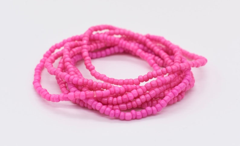 Puede incluir: Un conjunto de pulseras de cuentas rosadas. Las pulseras est&aacute;n hechas de peque&ntilde;as cuentas redondas que est&aacute;n enhebradas en un cord&oacute;n delgado.